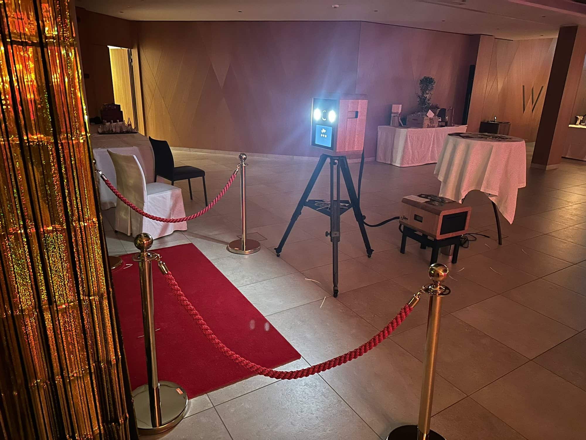 Fotobox am Firmenevent: roter Teppich zwischen goldenen Absperrpfosten führt zur Fotobox in einer Lobby