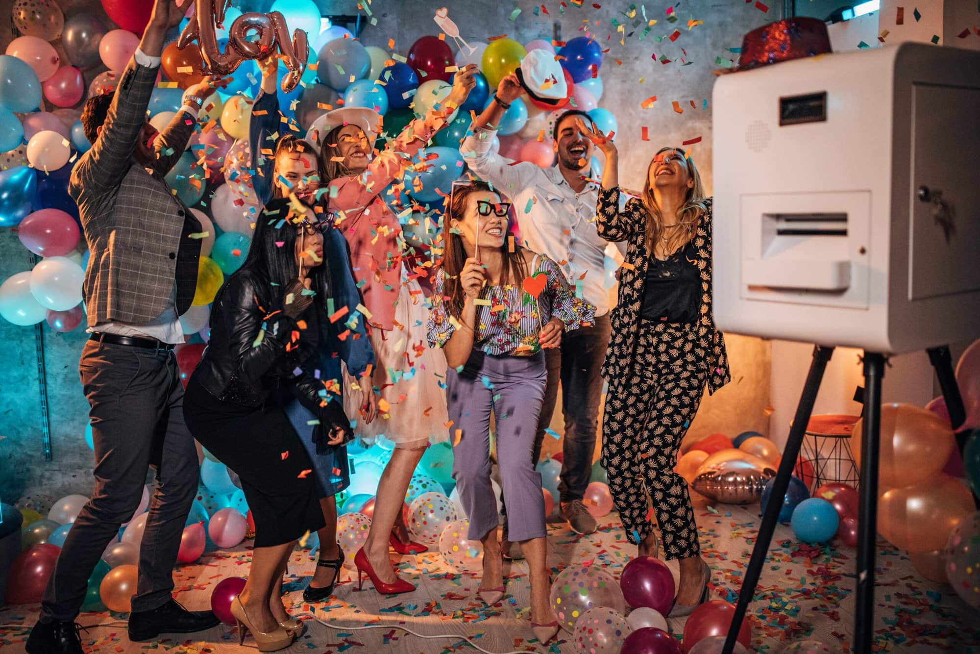 Gäste feiern mit Konfetti und Requisiten vor der Ballonwand, rechts die Jidori-Fotobox am Geburtstag