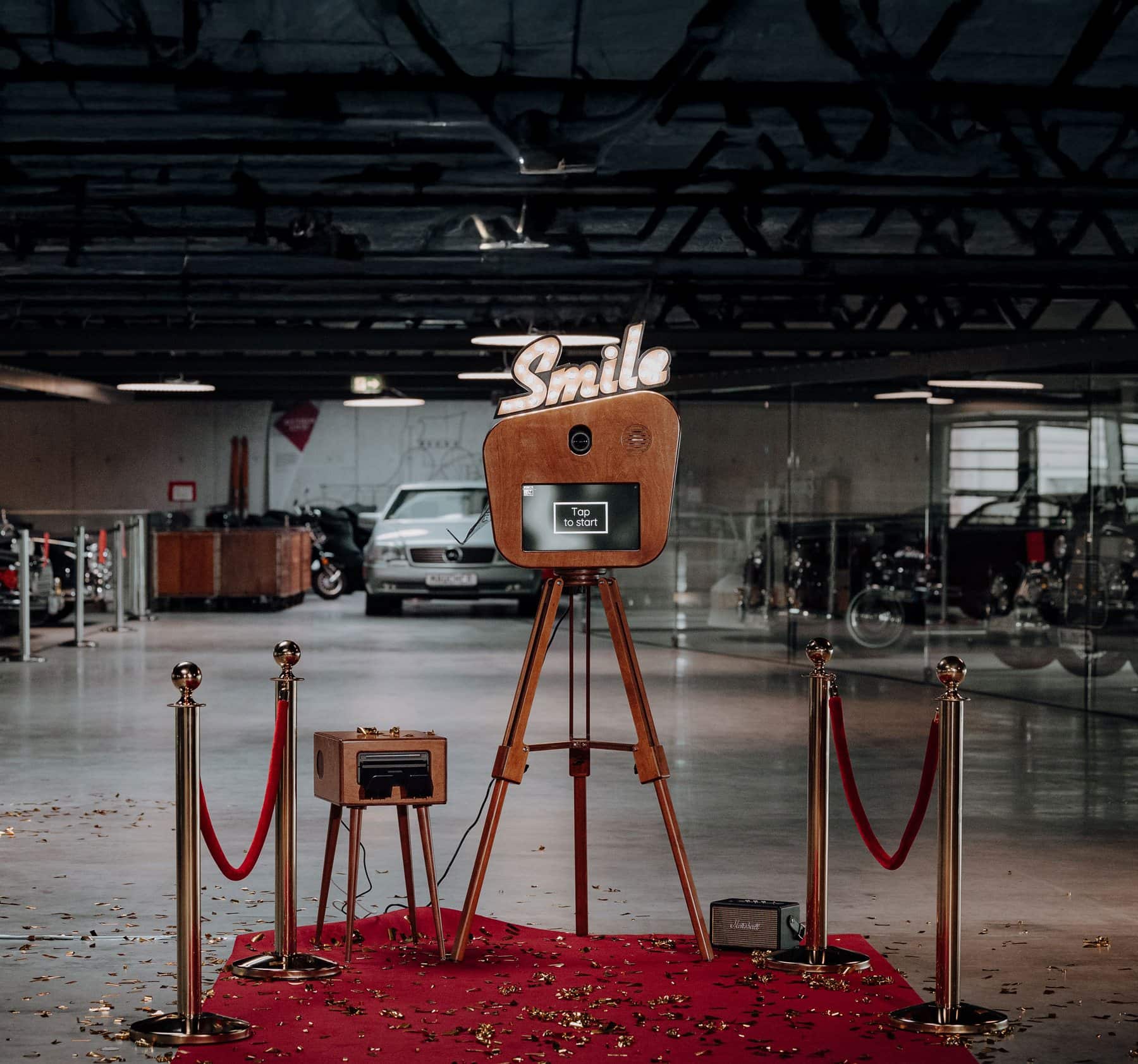 Fotobox mieten mit rotem Teppich und goldenen Absperrpfosten, aufgebaut vor Oldtimern