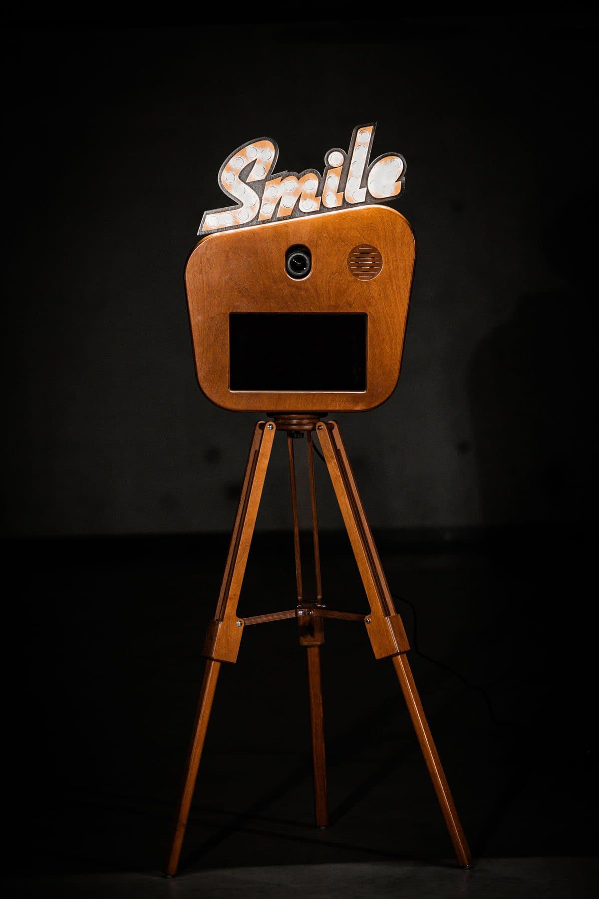 Fotobox «Smile» mieten: Holzbox mit leuchtendem Smile-Schild aus Glühbirnen auf Holzstativ, Studioaufnahme