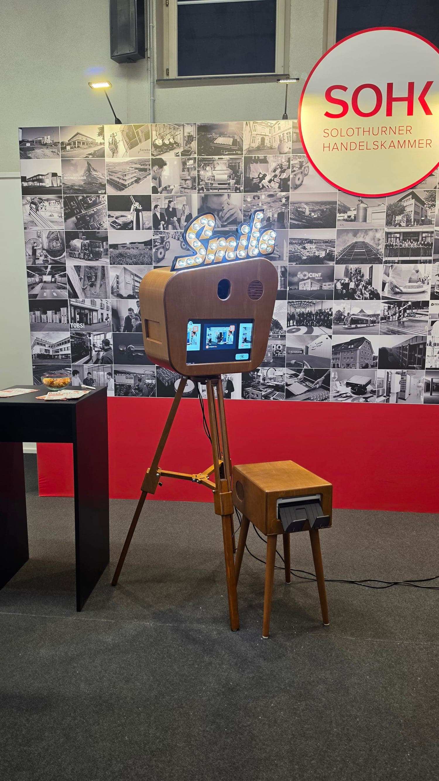 Fotobox «Smile» mit Druckerkonsole vor der Fotowand der Solothurner Handelskammer